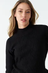 Sweater tejido color rosa con cuello alto y diseño de trenzas en el frente.