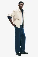 Jean de corte baggy confeccionado en denim de algodón rígido, con diseño de cinco bolsillos, tiro bajo y piernas amplias de silueta redondeada.