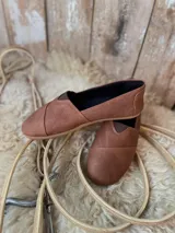 Alpargatas de cuero color marrón, con inserciones elásticas laterales y suela de goma.