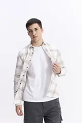 Camisa de manga larga confeccionada en viyela de algodón con diseño de cuadros en tonos neutros. Presenta cierre frontal con botones y bolsillo en el pecho.