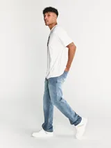 Pantalón de jean corte recto, color azul lavado, con diseño clásico de cinco bolsillos, cierre de cremallera y detalles de marca en remaches y parches traseros.