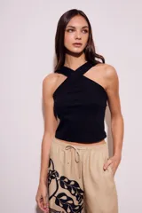 Top negro de tejido acanalado, corte cropped y escote halter cruzado en el frente.