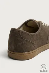 Zapatilla deportiva barefoot fabricada en piel con acabado serraje de color marrón, con cordones en contraste y suela fina de goma.