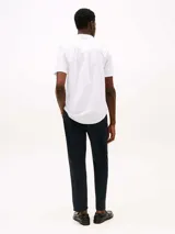 Camisa de manga corta blanca de Tommy Hilfiger confeccionada con popelín elástico de algodón BCI, con cuello abotonado, cierre con botones, detalles distintivos de Tommy Hilfiger y logo de Tommy Hilfiger bordado en el pecho.