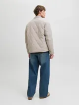 Campera acolchada liviana con diseño matelasse, cuello estilo baseball y cierre frontal con botones a presión. Cuenta con bolsillos frontales tipo parche y un bolsillo pequeño en el pecho con etiqueta de marca. Presenta puños elásticos y un corte recto funcional.