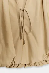 Cuerpo corto de cuello redondo con frunces, escote en pico con lazada y mangas cortas abullonadas con elástico interior.