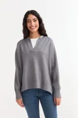 Sweater de tejido de punto color gris, con cuello en V abierto, mangas largas con puños acanalados y diseño holgado con tajos laterales en el ruedo.