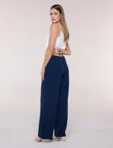 Pantalón wide leg blanco con finas rayas verticales oscuras, tiro alto, bolsillos laterales y pinzas frontales. Incluye un cinturón trenzado de rafia con hebilla rectangular.