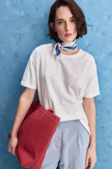Remera blanca de calce amplio, confeccionada en algodón liviano y respirable, con cuello redondo, mangas cortas y hombros caídos.