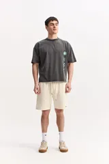 Remera de algodón marca Mistral, de corte boxy manga corta con efecto acid wash y estampas geométricas en color celeste dispuestas verticalmente sobre el frente.