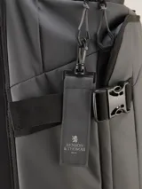 Valija gris con ruedas, manija extensible y correas de ajuste externas.