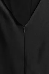 Vestido largo de satén con cuello halter y escote fluido. Presenta un diseño de espalda descubierta con cierre de cremallera oculta y lazada ajustable en el cuello.