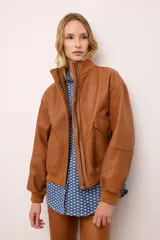 Chaqueta de cuero estilo bomber, con cuello alto, puños y cintura de tejido de punto acanalado. Presenta cierre frontal con cremallera y dos bolsillos laterales con solapa.