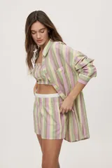 Short a rayas verticales en tonos verde, lila, amarillo y marrón, con tiro medio, cintura elástica en contraste y bolsillos laterales, de calce relajado.