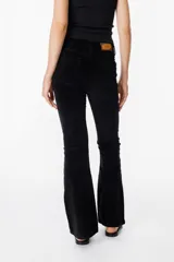 Pantalón de jean tipo pana color negro, de corte acampanado y tiro medio, con cierre frontal y bolsillos laterales.