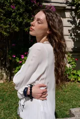 Blusa rosada de manga larga con escote en V, volados frontales con ribete negro contrastante y puños elásticos.