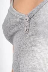 Vestido midi gris de punto canalé, con breteles finos y escote en V con botones decorativos.