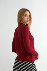 Polera de tejido de punto fino color bordó, con cuello alto y mangas largas.