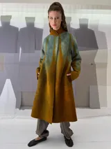 Tapado largo de fieltro de lana merino con teñido artesanal tie-dye en degradé de azul. Tiene cuello alto, cierre lateral con broches ocultos, bolsillos laterales y corte amplio.