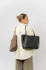 Cartera tipo tote de diseño amplio y estructurado, confeccionada en material sintético con textura graneada. Cuenta con doble asa larga para llevar al hombro y logo de la marca aplicado en el frente.