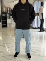 Canguro negro oversize de felpa, con capucha, bolsillo tipo canguro y diseño estampado en la espalda con gráficos estilo streetwear y texto en blanco.