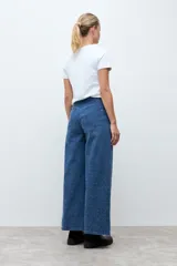 Pantalón de jean de corte recto y tiro alto, confeccionado en denim azul con una textura sutil de pequeños puntos en relieve.