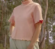 Remera de punto color verde claro, con cuello alto y mangas cortas con terminación ondulada.