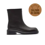 Bota corta de cuero negro con diseño minimalista, costura central visible en el empeine y suela plana de goma con pequeño taco cuadrado.