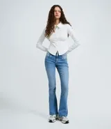 Pantalón de jean modelo boot cut en color azul claro, con cintura baja, cierre frontal con doble botón y cremallera, bolsillos funcionales y trabillas para cinturón.