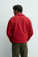 Sudadera de corte regular fit color rojo, con cuello subido y cierre frontal de cremallera. Presenta mangas largas y acabados en rib en puños y ruedo.