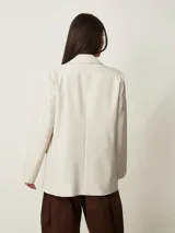 Blazer beige claro de corte recto, con solapas de muesca, mangas largas y bolsillos frontales.