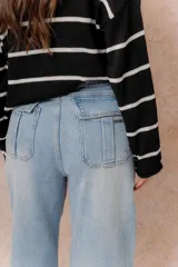 Jean wide leg de tiro alto en denim color celeste claro. Presenta un diseño de cinco bolsillos, destacándose los bolsillos traseros con solapa y detalle de marca metálica. Posee cierre frontal con botón y ruedo recto.