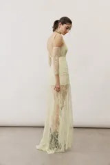Vestido largo blanco de encaje con diseño asimétrico, tirante fino en un hombro y falda transparente.