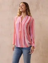 Blusa de gasa estampada con flores en tonos rosa, amarillo y azul. Tiene cuello a la base, escote en V y botones. La delantera tiene detalle plisado y las mangas son 3/4 regulables con presilla y botón.