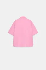 Camisa azul de manga corta y cuello solapa con costura horizontal en el pecho y cierre frontal oculto con botones.