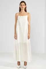 Vestido largo color crema de lyocell, poliamida y lino, con breteles finos, escote recto, lazos en los costados y forro hasta arriba de las rodillas.