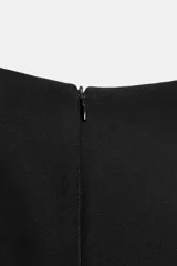 Vestido mini negro con cuello redondo, manga corta con pliegues y costuras marcadas. Cuenta con cierre posterior con cremallera oculta.