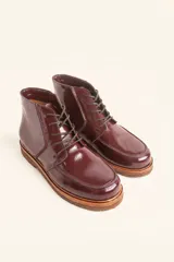 Bota acordonada de cuero vacuno con acabado charol color suela, con suela de goma tipo crepe y costuras reforzadas.