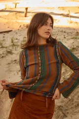 Sweater de lana de cordero con cuello a la base y manga larga. Presenta un diseño de franjas verticales combinando tejido de punto con detalles en crochet y cintas de lúrex brillante.