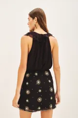 Falda corta cruzada con diseño envolvente y lazo lateral para ajuste. Presenta bordados florales detallados en toda la superficie, tanto en el frente como en la espalda. Está completamente forrada para mayor comodidad.