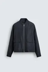Sobrecamisa de corte regular fit en tejido técnico negro resistente al agua, con cuello estilo bomber en rib elástico, cierre frontal de cremallera y bolsillos plastrón con solapa en la cadera.