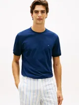 Remera de corte slim color azul marino, con cuello redondo clásico, manga corta y detalle de doble raya en los puños. Presenta el icónico logo bordado de la bandera de Tommy Hilfiger en el pecho.