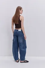 Jean negro de silueta barrel, tiro medio y pierna amplia que se curva hacia el ruedo. Cuenta con bolsillos delanteros y detalle de costuras decorativas.