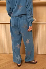 Pantalón azul con estampado de estrellas brillantes, de corte recto y fluido, cintura alta con trabillas para cinturón, cierre con botón y cremallera, bolsillos laterales.