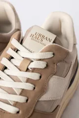 Championes urbanos de diseño técnico, combinando paneles de gamuza y tela en tono verde oliva con detalles en beige y negro. Presentan una suela de plataforma en color crema con base dentada en tono caramelo.