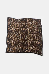 Pañuelo cuadrado con estampado animal print de leopardo en tonos marrones y beige, con borde negro. Confeccionado en hilatura con seda.
