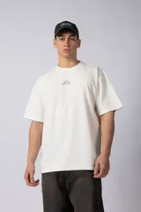 Remera color crudo de corte oversize, con cuello redondo y mangas cortas. Presenta un pequeño bordado de un sol en el centro del pecho.