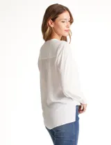 Blusa de gasa blanca, marca Catherine Malandrino, con cuello a la base y escote en V pronunciado. Incluye una pieza interna a tono para un escote discreto. Tiene manga larga con puño ancho y botón.