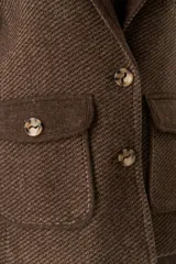 Abrigo de cuello sastre color beige, con forro, cierre frontal con botones, bolsillos con solapa y presillas en mangas. Confeccionado en lana fina sin teñir, diseñado exclusivamente por Don Baez.