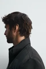 Cazadora acolchada de cuello subido, color negro, con mangas largas de tejido elástico. Incluye bolsillos en la cadera, un bolsillo interior y bajo con elástico. Cierre frontal de cremallera.